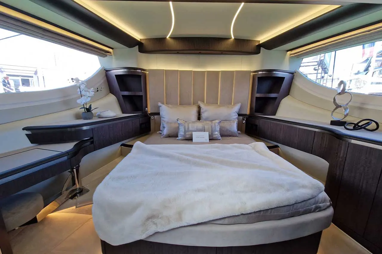 Luxurious boat interior featuring a plush bed with decorative pillows, soft blanket, and elegant decor, illuminated by cozy lights.