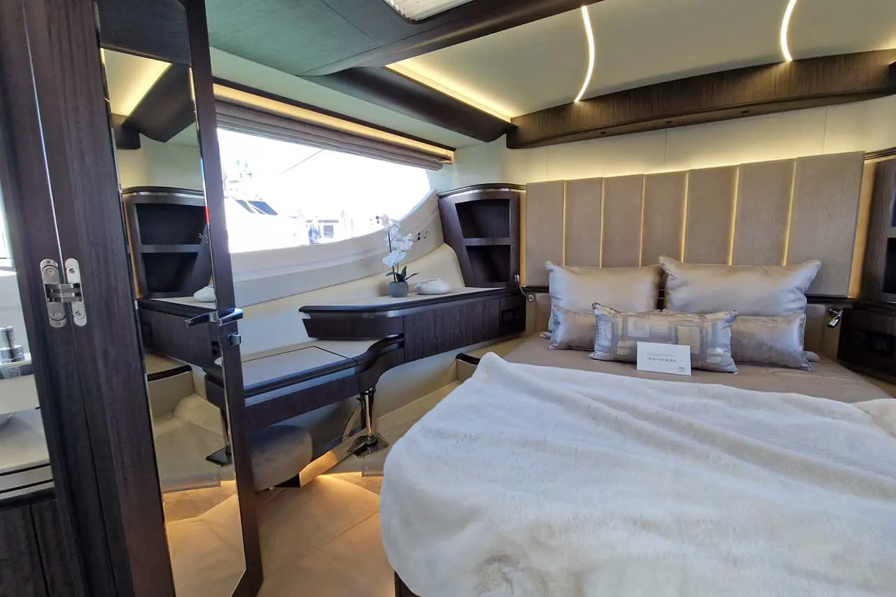 Luxurious yacht interior featuring a cozy bed with decorative pillows, a mirrored closet, and elegant decor.
