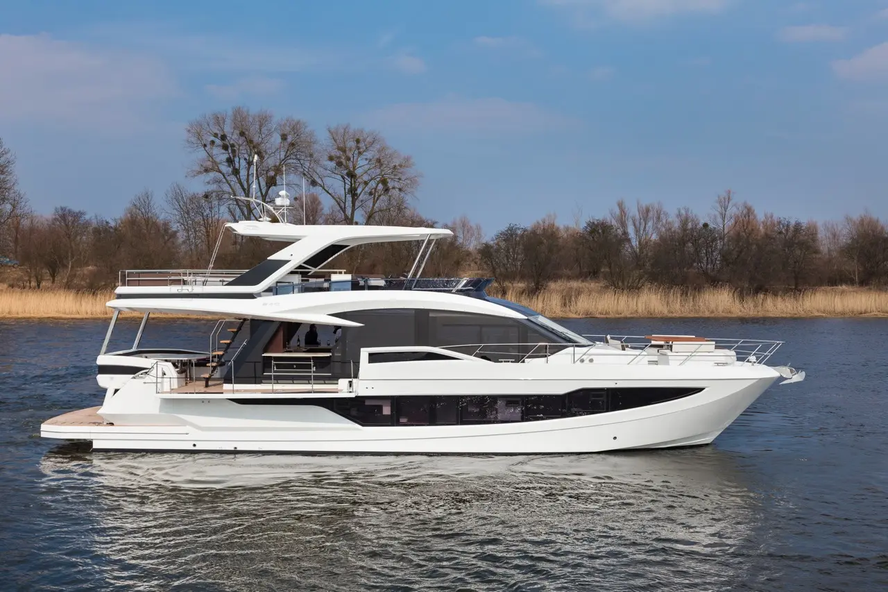 Luxurious white yacht gliding on water, surrounded by trees and reeds under a clear blue sky, showcasing modern design.