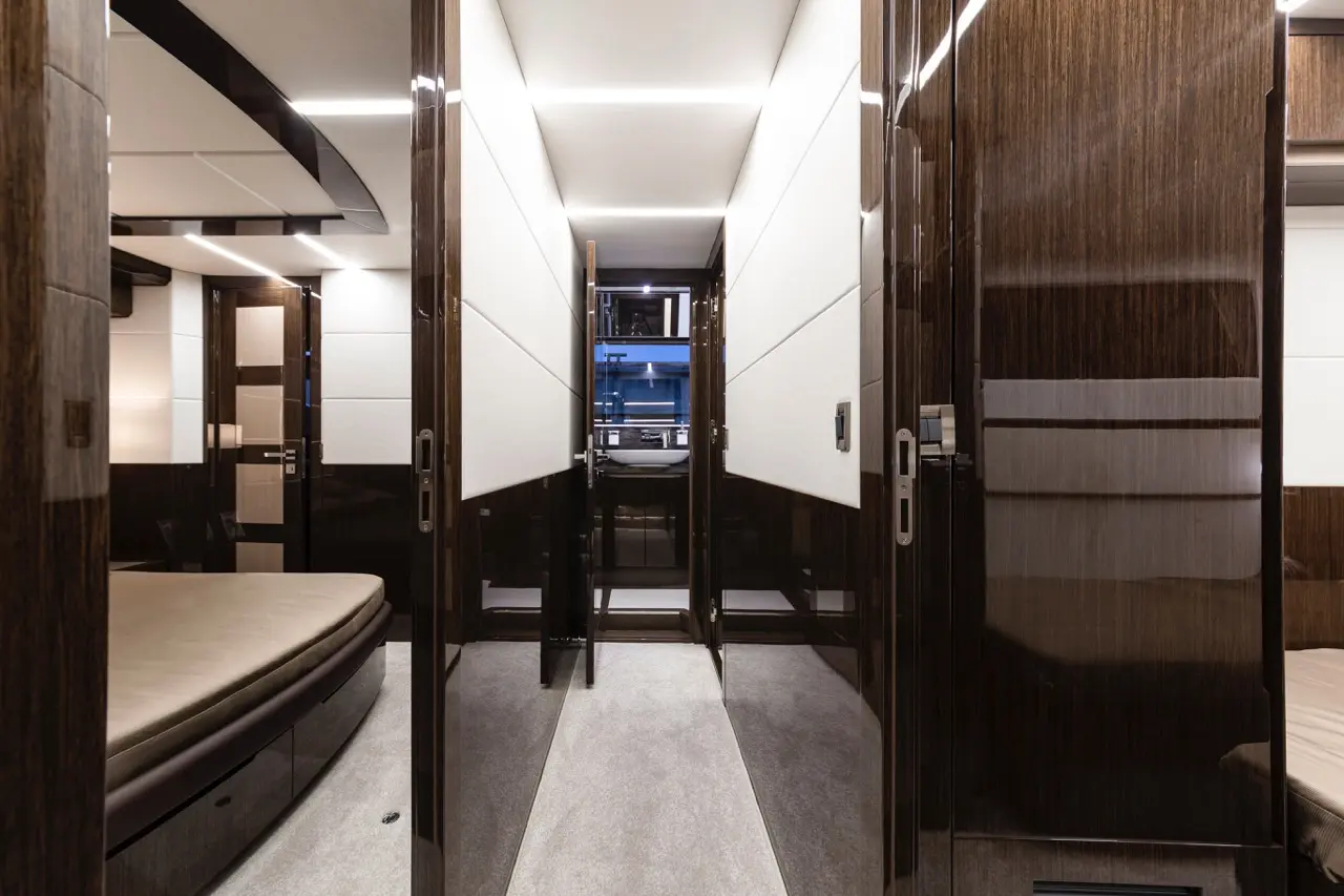 Luxurious interior of a modern yacht with elegantly designed corridor, plush bedding, and polished wooden doors.