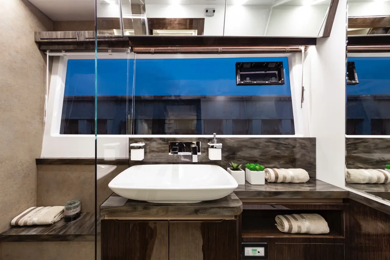 Modern bathroom with a white basin, grey stone countertop, mirror, and a window revealing a blue sky.