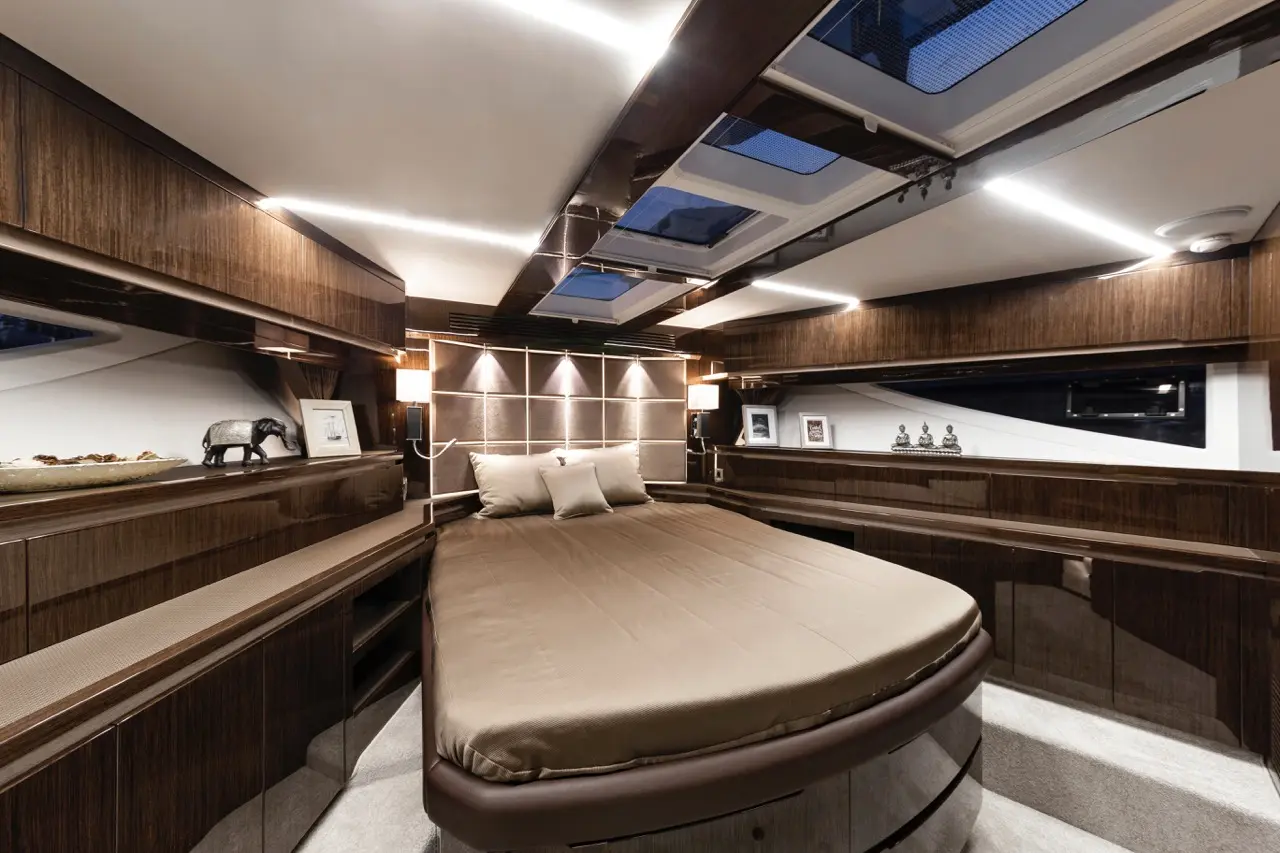 Luxurious yacht cabin featuring a round bed, wooden cabinetry, large windows, and subtle lighting for a sophisticated ambiance.