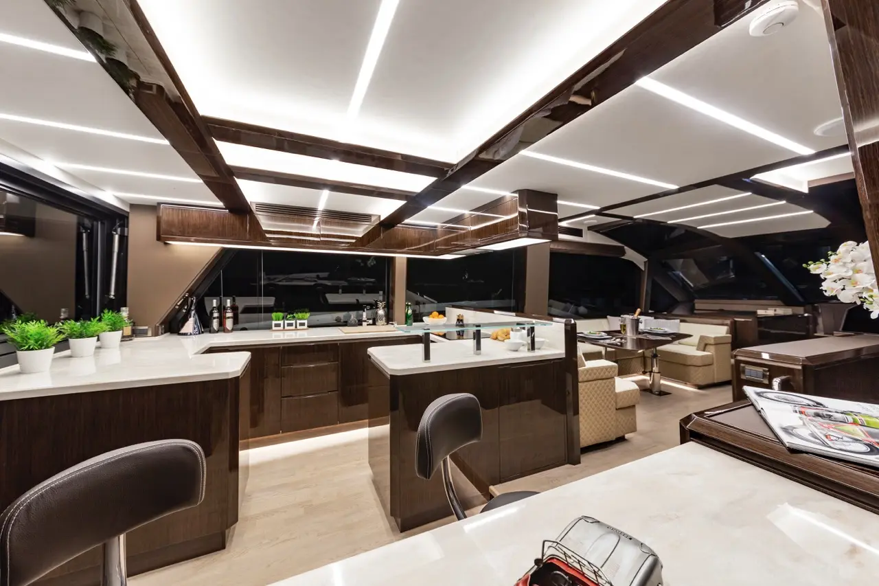 Sleek yacht interior featuring a modern kitchen with marble countertops, elegant lighting, and stylish seating areas.