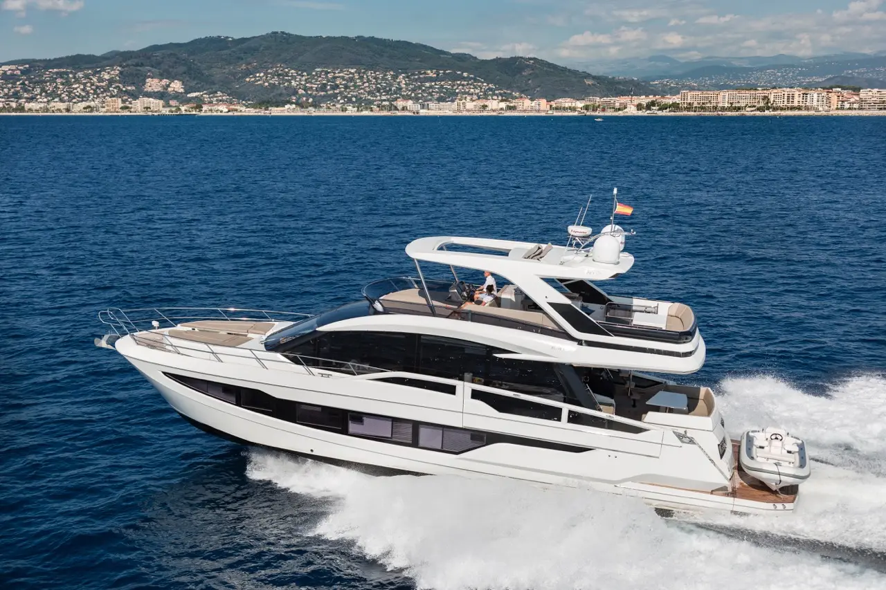 Luxury motor yacht cruising through blue waters, with scenic coastal hills in the background. Ideal for upscale boating experiences.