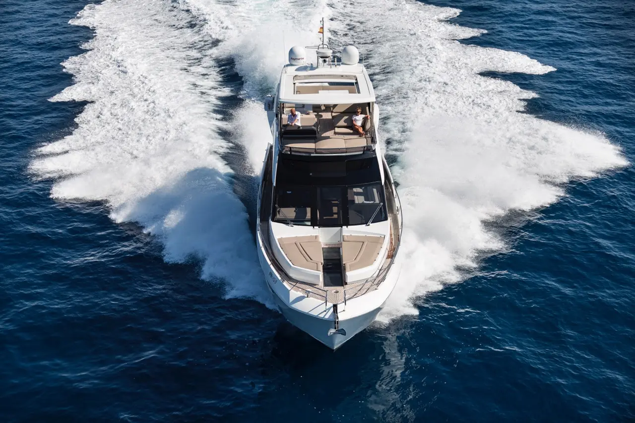 Luxury motorboat cruising through deep blue waters, leaving a trail of white frothy waves in sunny weather.
