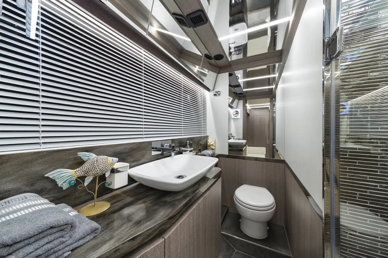 Modern bathroom with a grey towel, decorative fish, sink, toilet, and sleek mirror above a stylish countertop.