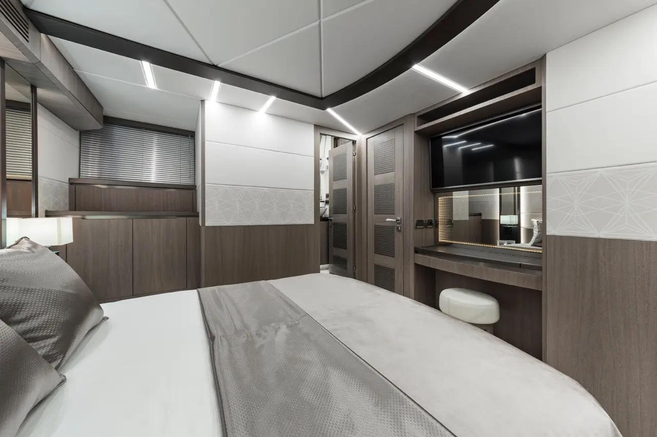Modern bedroom interior featuring a large bed, wooden furniture, a TV, and stylish lighting.