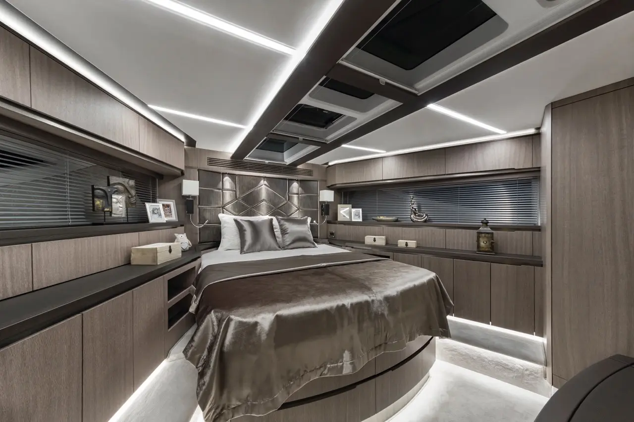 Luxury bedroom with a round bed, sleek wooden furniture, and modern lighting, featuring decorative items on shelves.
