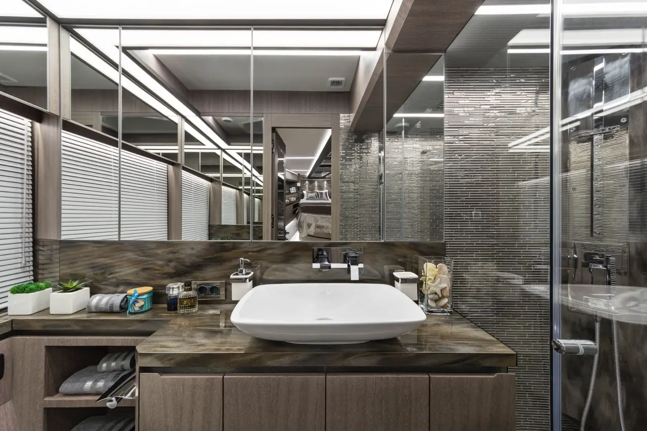 Modern bathroom with a stylish sink, mirrors, and decorative items on a marble countertop, showcasing sleek design and functionality.
