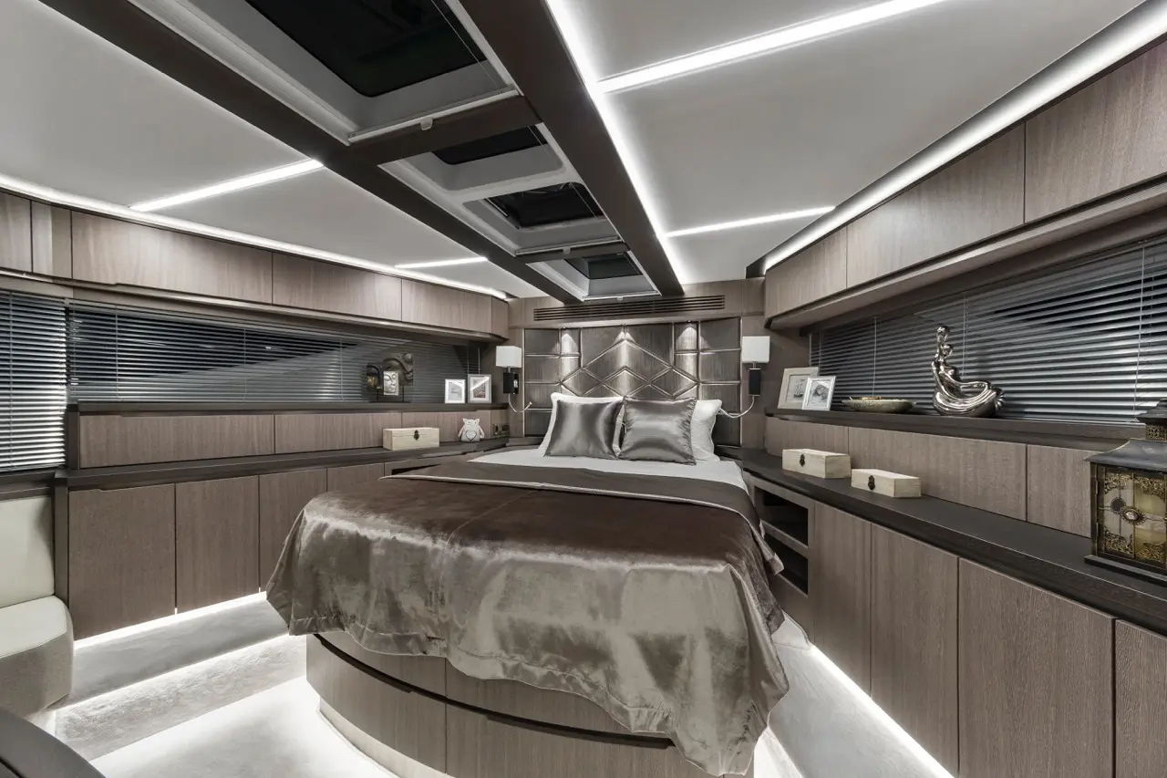 Luxury bedroom featuring a king-sized bed with silver bedding and modern decor, illuminated by sleek ceiling lights.