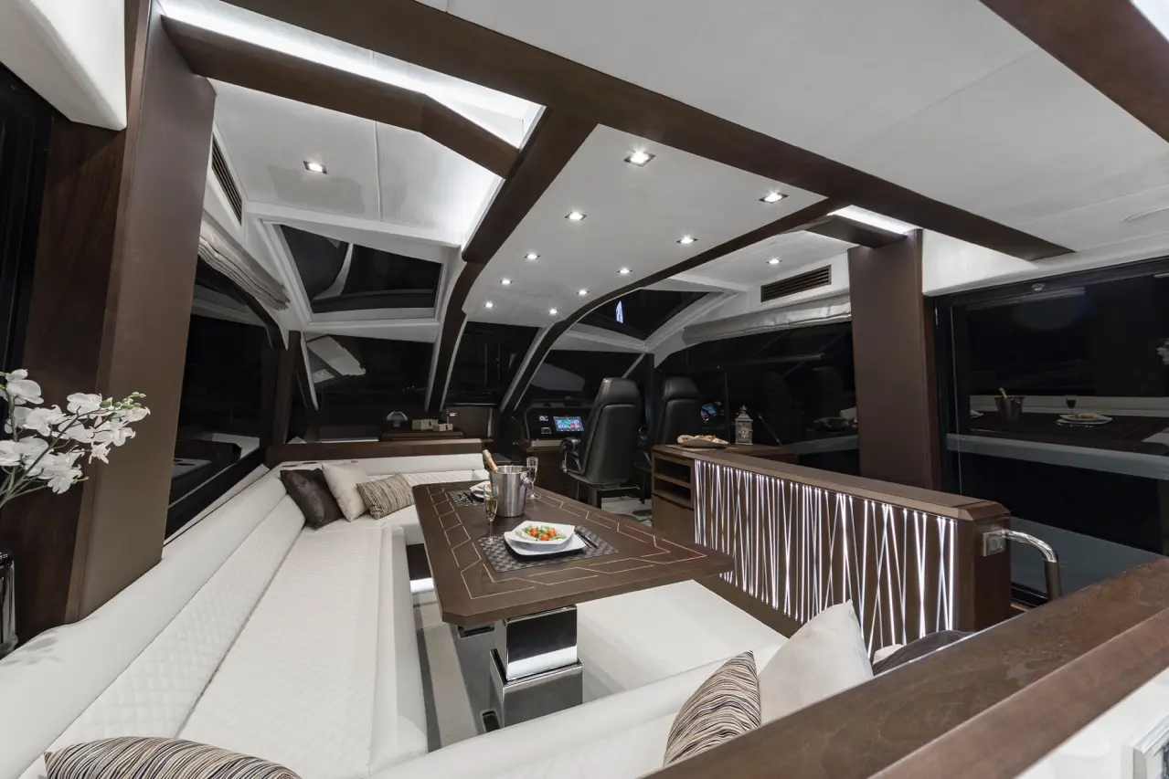 Luxurious yacht interior featuring modern seating, dining table, and ambient lighting, with a view through large windows.