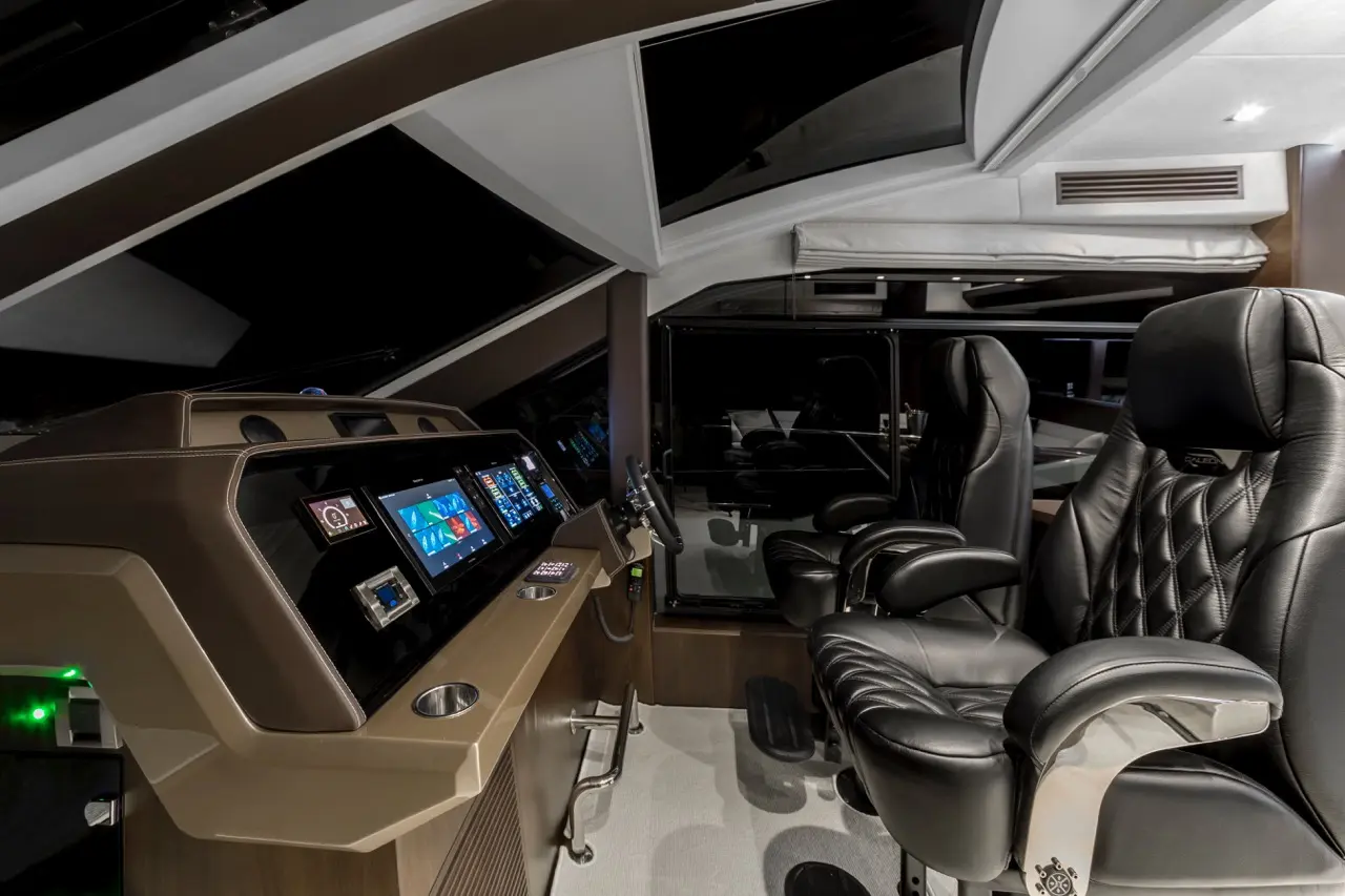 Luxury boat cockpit featuring advanced control panels, large screens displaying navigation data, and ergonomic leather seating.