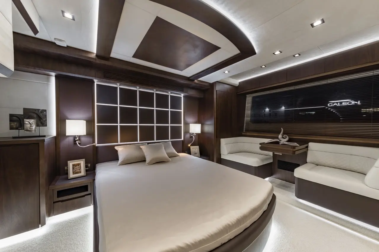 Luxurious bedroom featuring a round bed, subtle lighting, stylish artwork, and a comfortable seating area by the window.