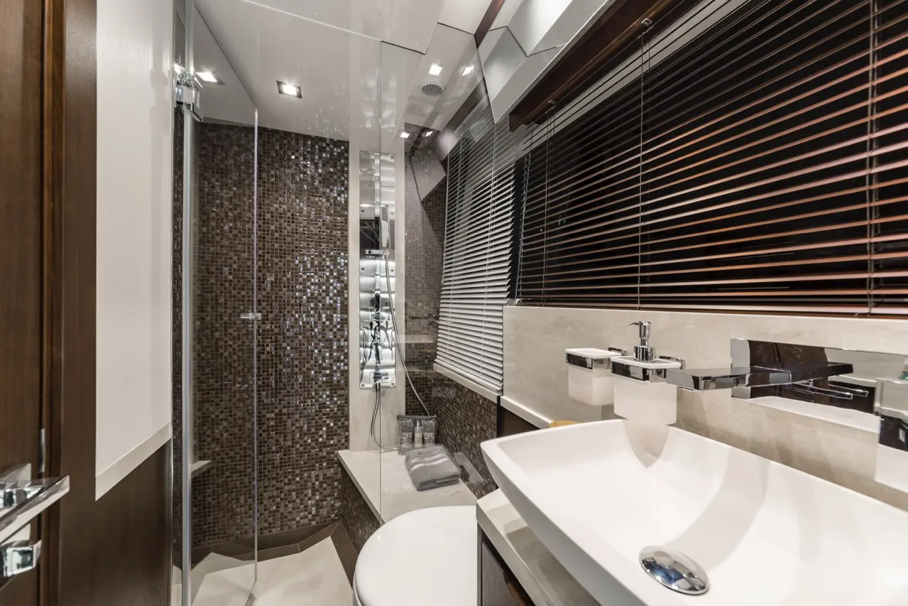 Modern bathroom featuring a glass shower, sleek basin with chrome taps, and mosaic accent wall, illuminated by recessed lighting.