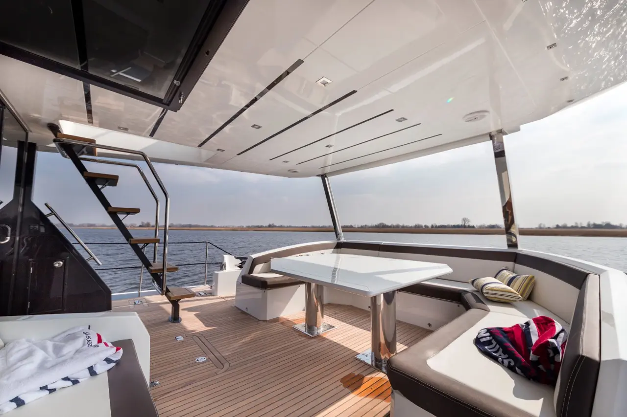 Stylish outdoor seating area on a yacht featuring a sleek table, plush cushions, and a scenic water view.