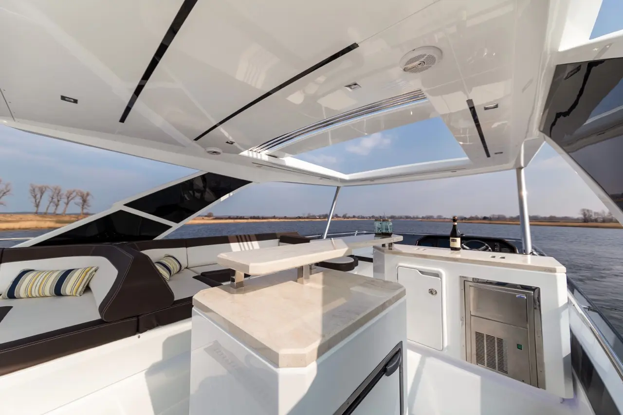 Luxury boat interior featuring a seating area, bar countertop, and panoramic windows overlooking a serene water view.