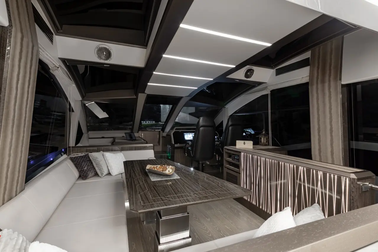 Modern yacht interior showcasing a sleek lounge with white seating, wooden table, and panoramic windows.