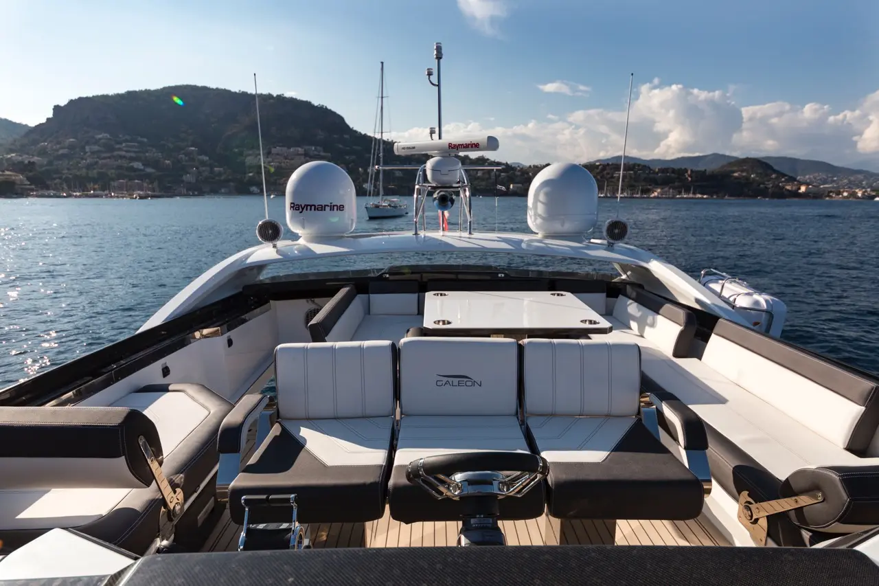Luxury yacht interior featuring Galeon seats and Raymarine equipment, overlooking calm waters and a mountainous shoreline.