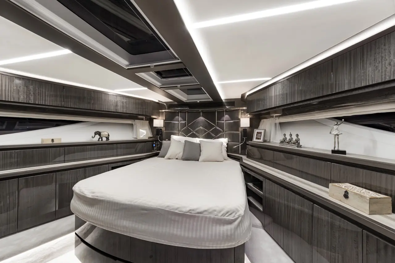 Luxury yacht interior featuring a modern bedroom with a round bed, elegant lighting, and decorative items on shelves.