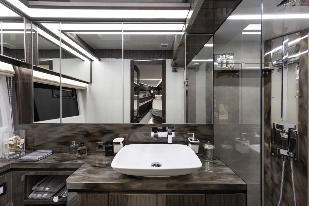 Modern bathroom featuring a stylish sink, wall mirrors, and sleek lighting, with toiletries arranged neatly on the countertop.