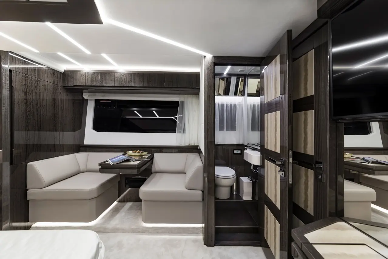 Luxury yacht interior featuring modern lounge area, kitchenette, and bathroom with subtle LED lighting and stylish finishes.