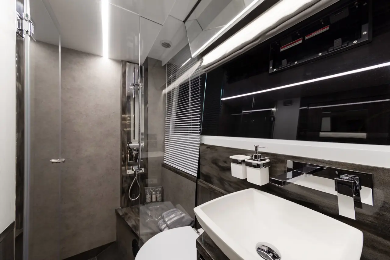Stylish modern bathroom with a glass shower, sleek sink, and minimalist design features, illuminated by strip lighting.