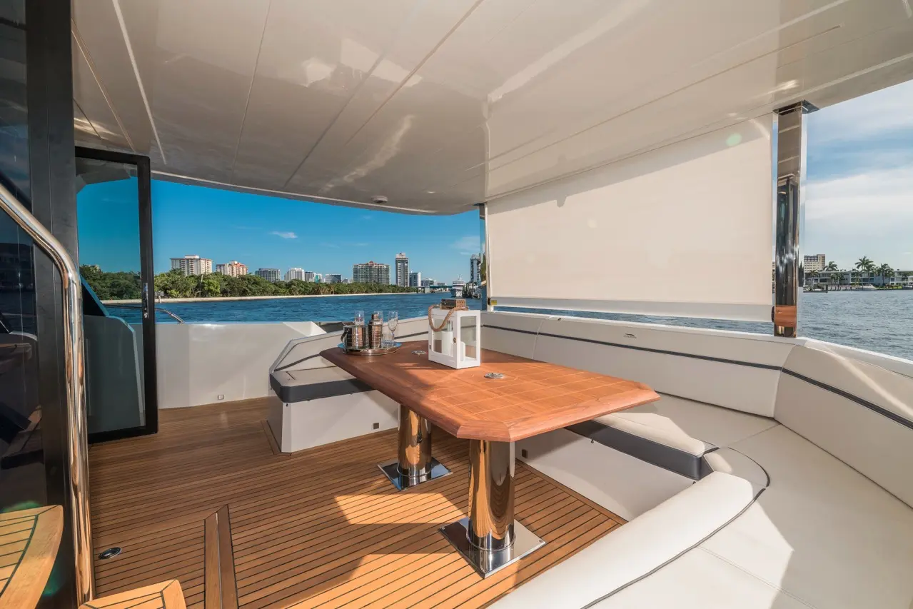 Luxury yacht interior with a wooden dining table, plush seating, and scenic views of the waterfront city skyline.