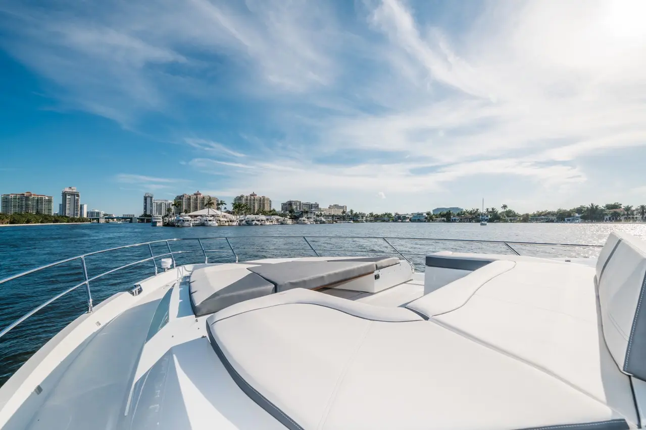 View from the bow of a luxury yacht, showcasing city skyline and waterfront under a clear blue sky.