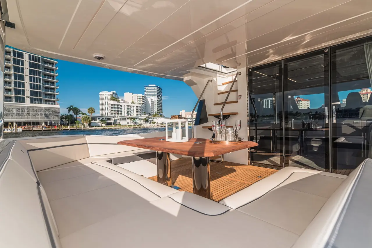 Luxury yacht deck featuring a wooden table, champagne, and city skyline views, perfect for entertaining.