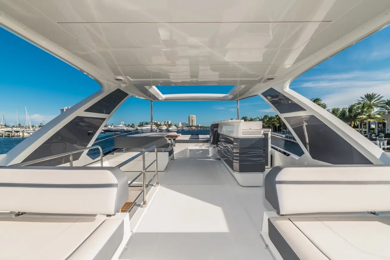 Luxurious yacht deck featuring modern seating, a helm area, and views of the marina against a clear blue sky.