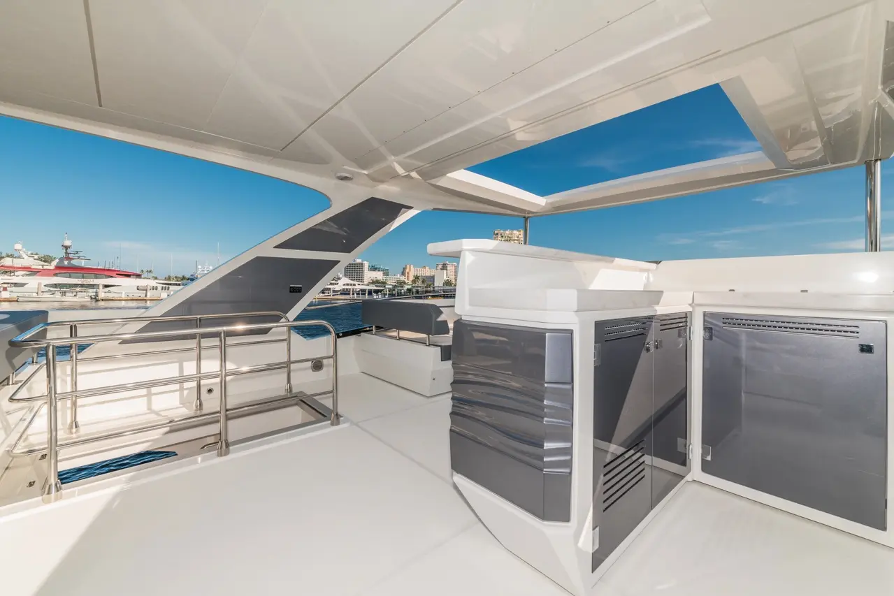 Spacious yacht deck featuring an outdoor kitchen area, stainless steel railings, and a view of the marina and skyline.