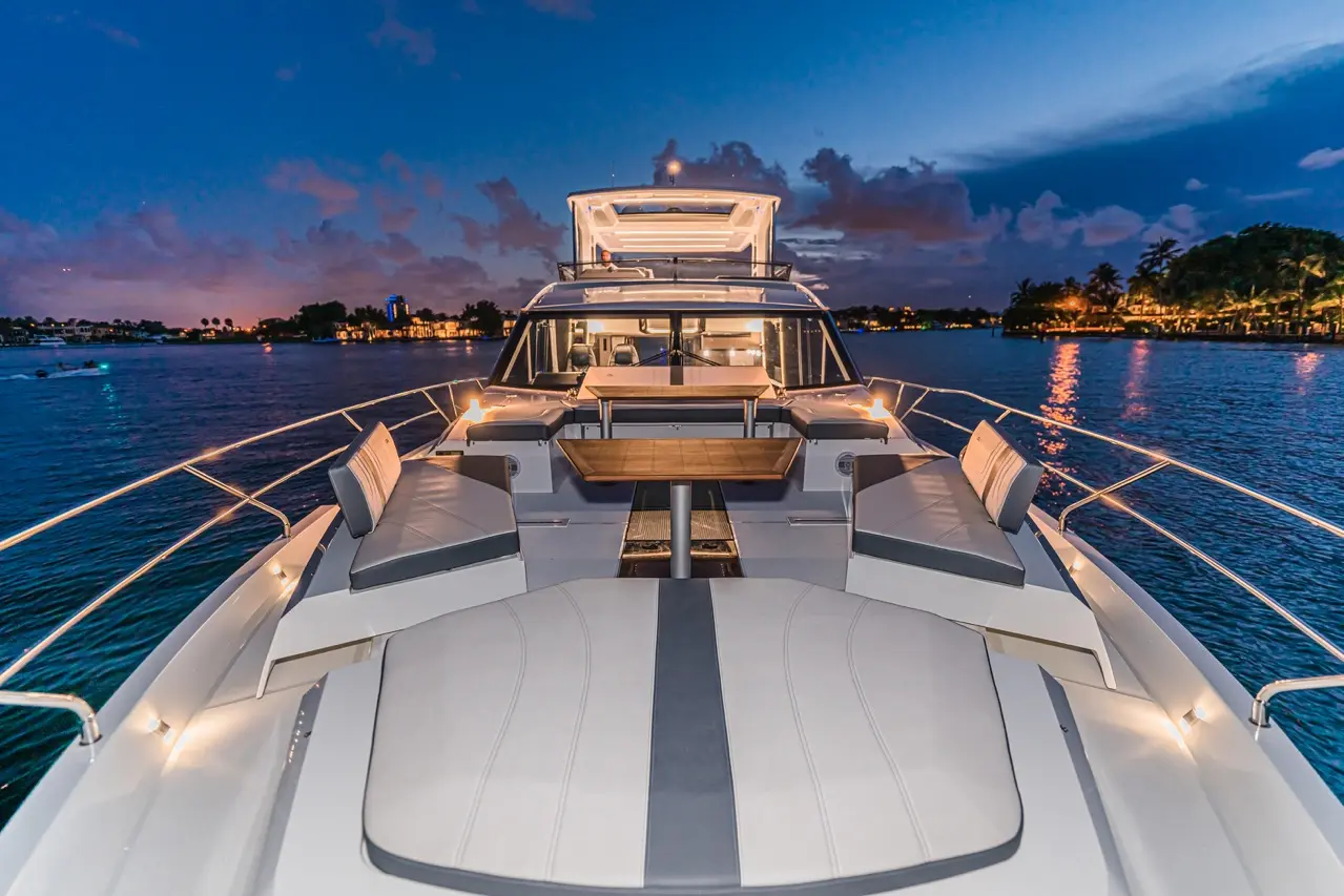 Luxury yacht deck with modern seating and a dining table, set against a serene twilight water backdrop.