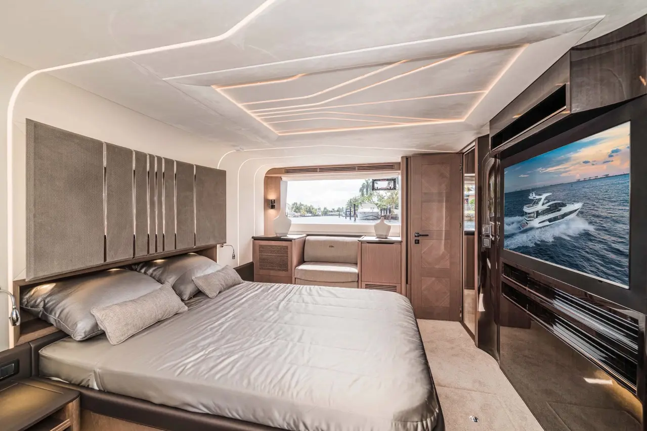 Luxurious yacht bedroom featuring a king-sized bed, elegant decor, large TV, and a view through a window.