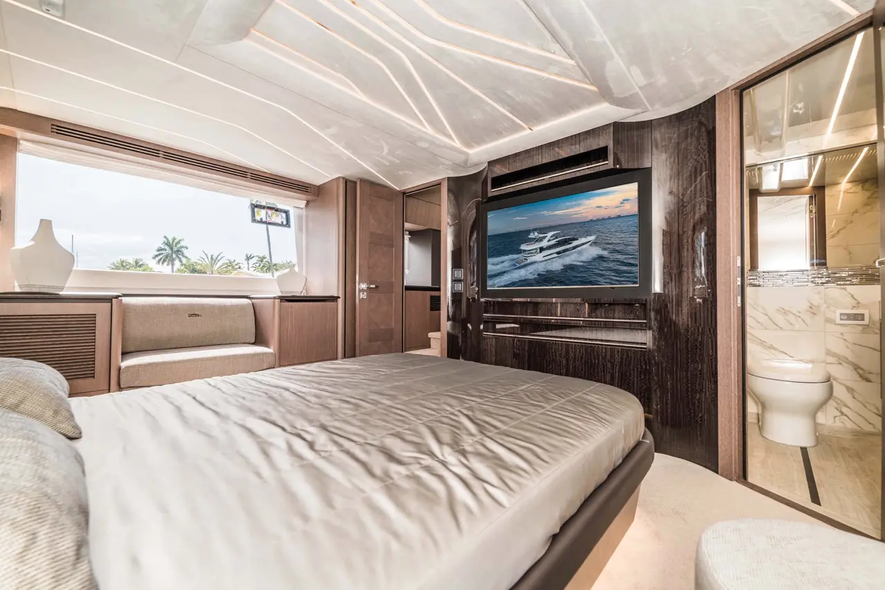 Luxury yacht bedroom featuring a large TV showing a boat at sea, soft furnishings, and a stylish interior design.