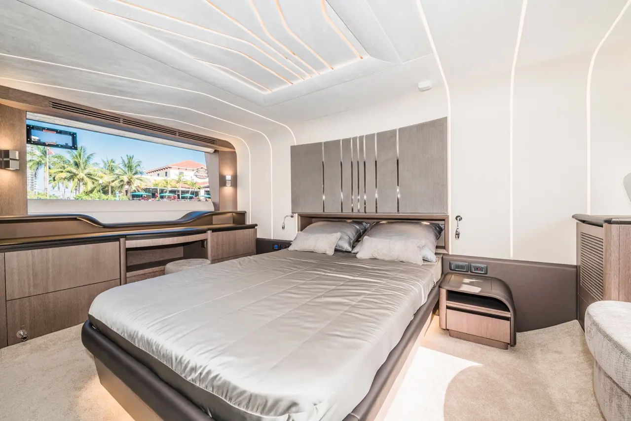 Modern bedroom interior featuring a double bed, stylish decor, and a large window with a view of palm trees outside.