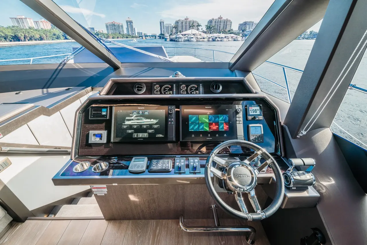 Luxury yacht cockpit with navigation screens, controls, and water view, displaying speed and other metrics.