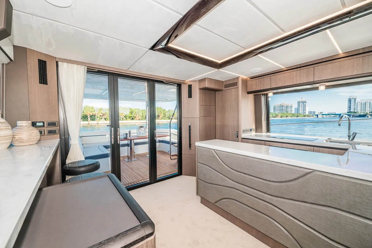 Modern boat interior featuring a sleek kitchen area, large windows, and scenic water views. Stylish furniture and decor.