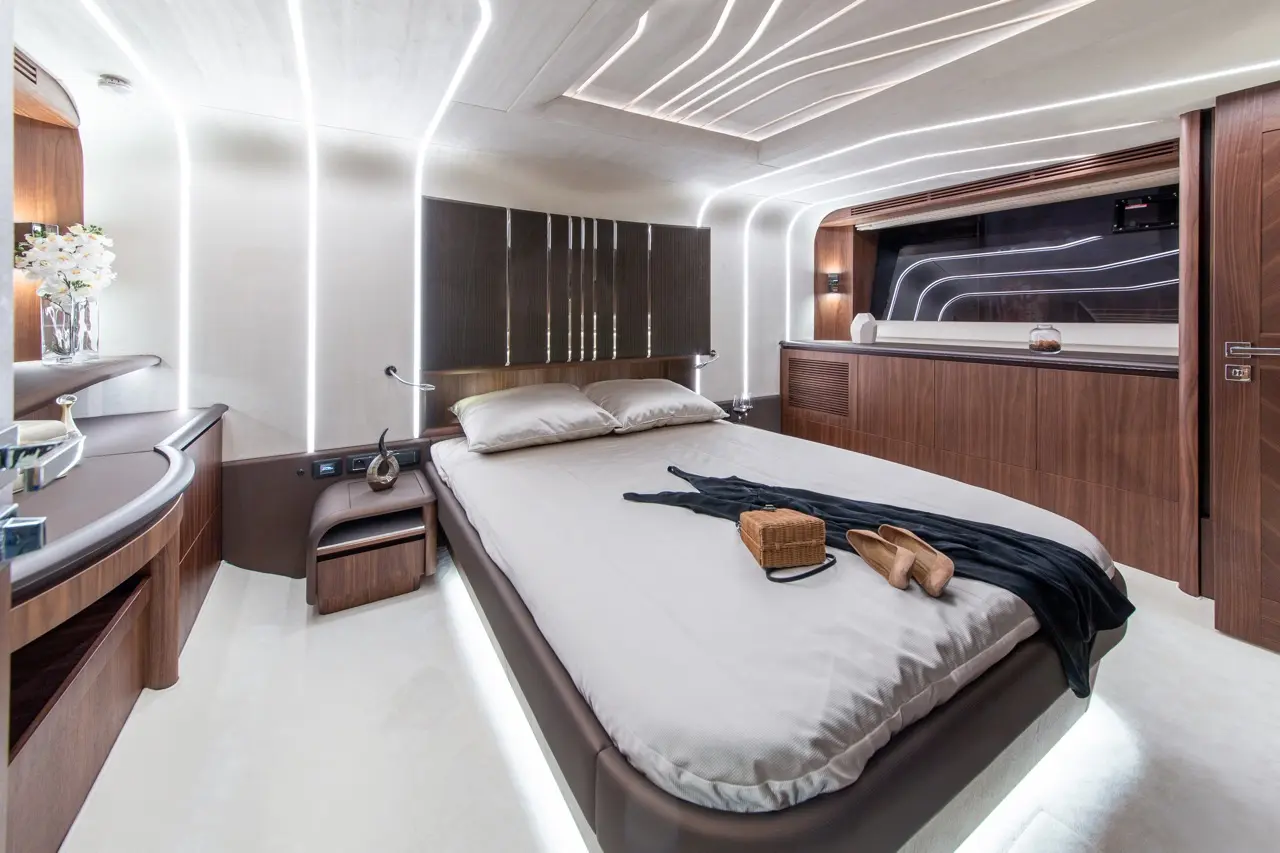 Modern bedroom featuring a large bed, wooden furniture, ambient lighting, and scattered personal items like footwear and a basket.