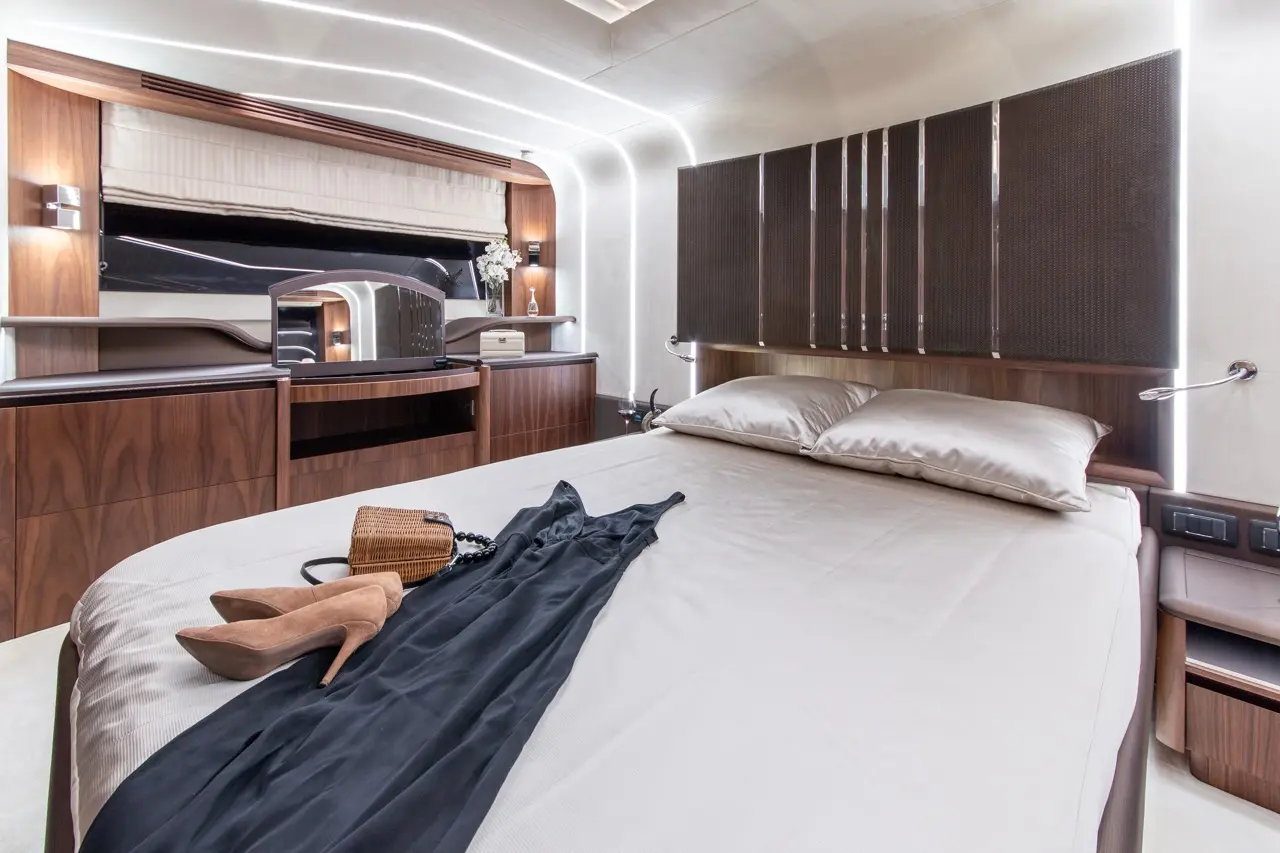 Modern bedroom featuring a double bed with elegant bedding, a stylish dress, heels, and a wooden vanity with decorative items.