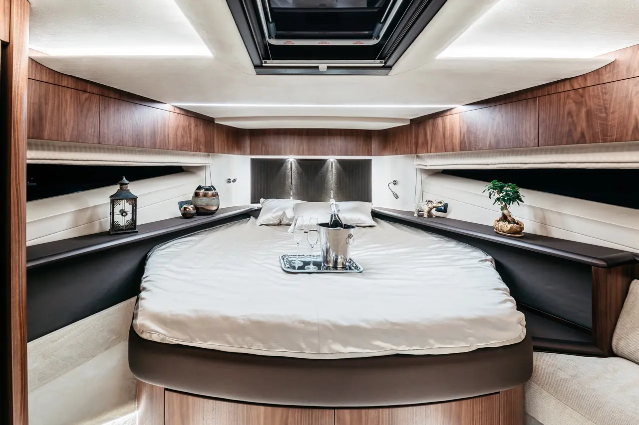 Luxurious boat cabin featuring a circular bed, champagne, glasses, decorative items, and ambient lighting.