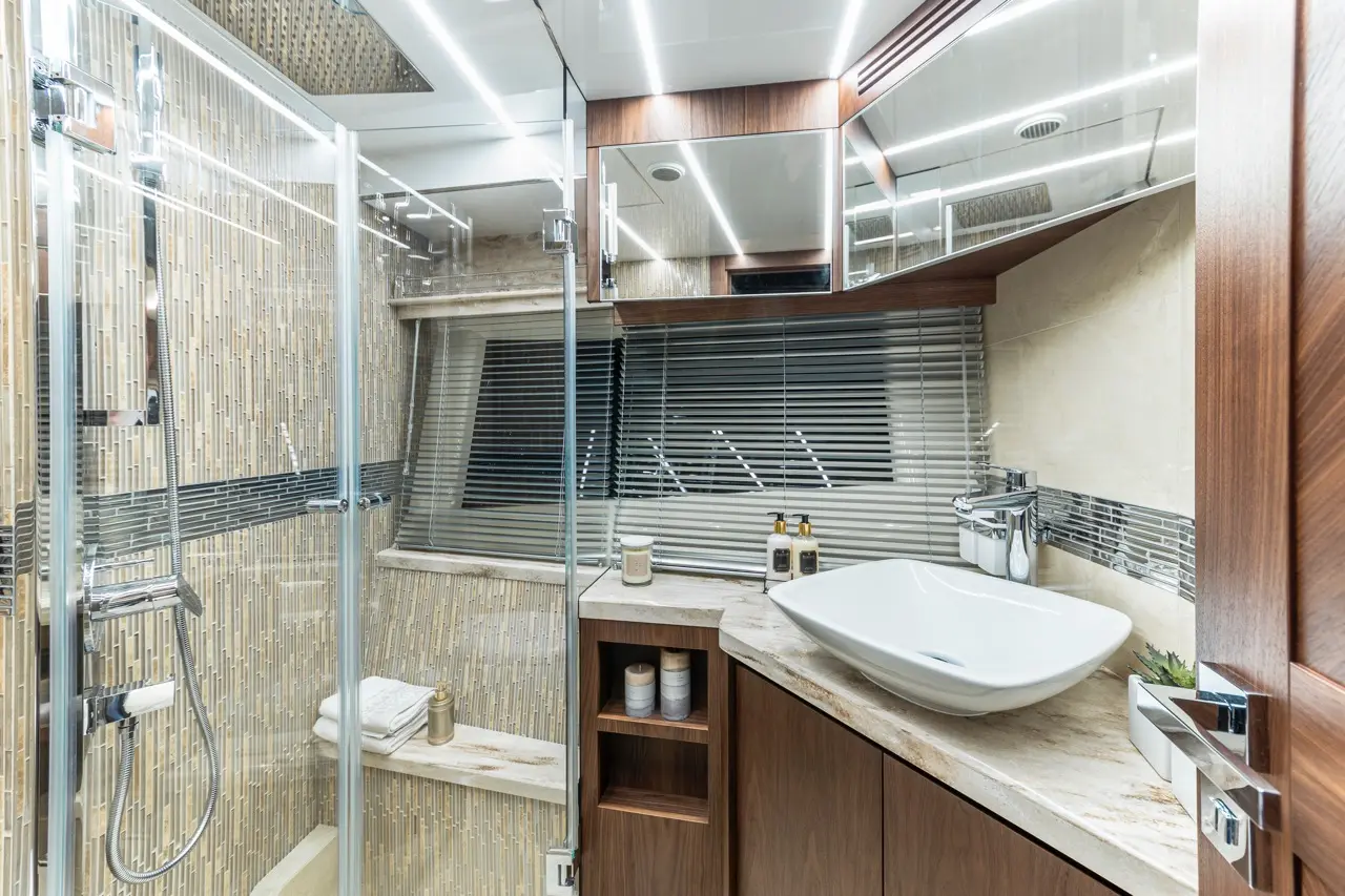 Modern bathroom with a glass shower, vessel sink, wooden cabinetry, and elegant decor, showcasing a minimalist style.