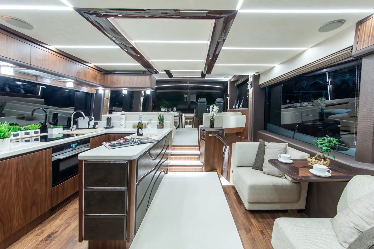 Luxurious yacht interior featuring a sleek kitchen, plush seating, and mood lighting, creating an elegant atmosphere.