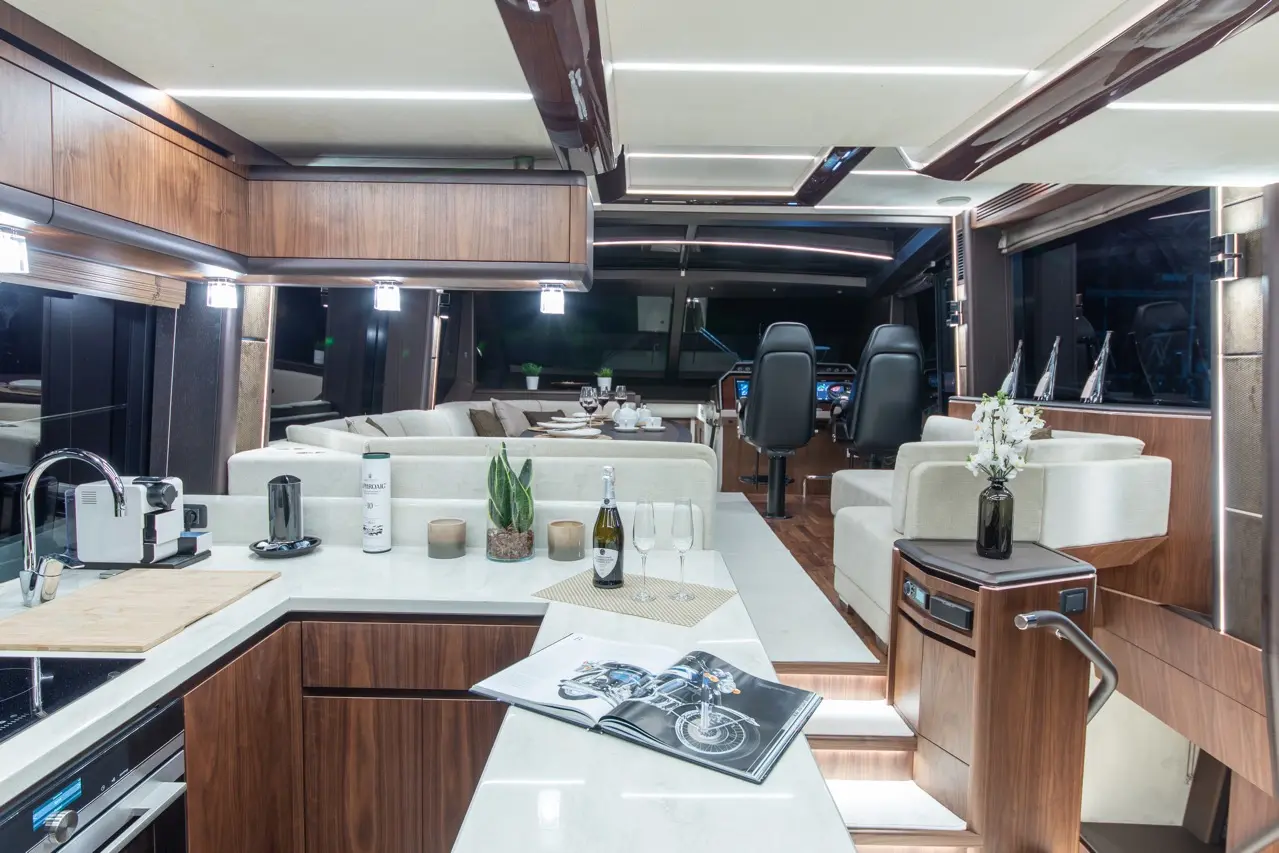 Interior of a luxury yacht featuring a modern kitchen, lounge area, and helm with a magazine on the counter.