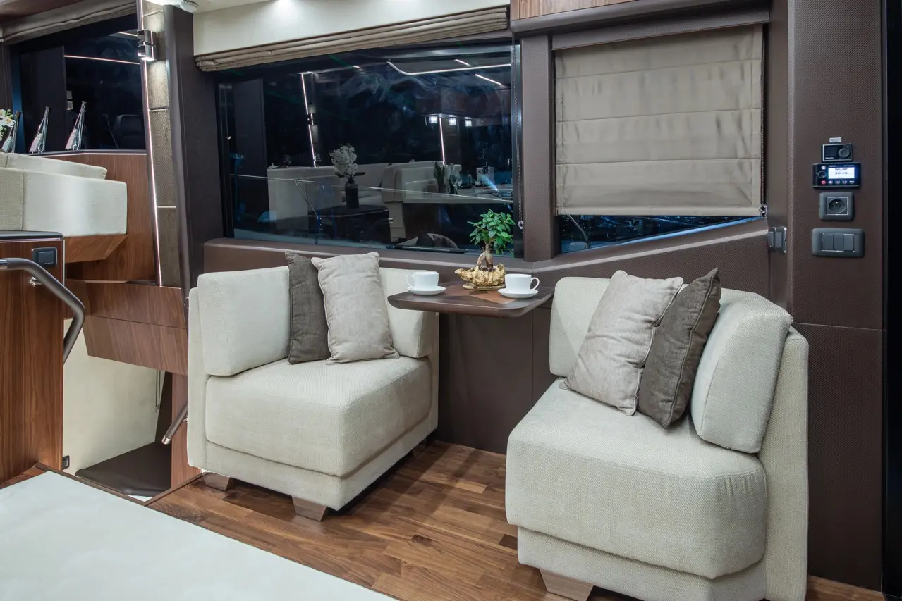 Modern lounge area with two plush armchairs, a side table, and decorative elements, featuring large windows and soft lighting.
