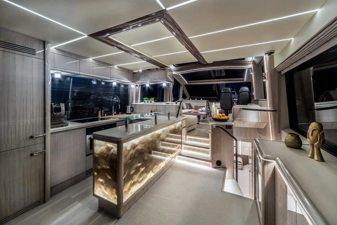 Luxurious yacht interior featuring a modern kitchen, illuminated steps, and elegant decor, including a decorative sculpture.
