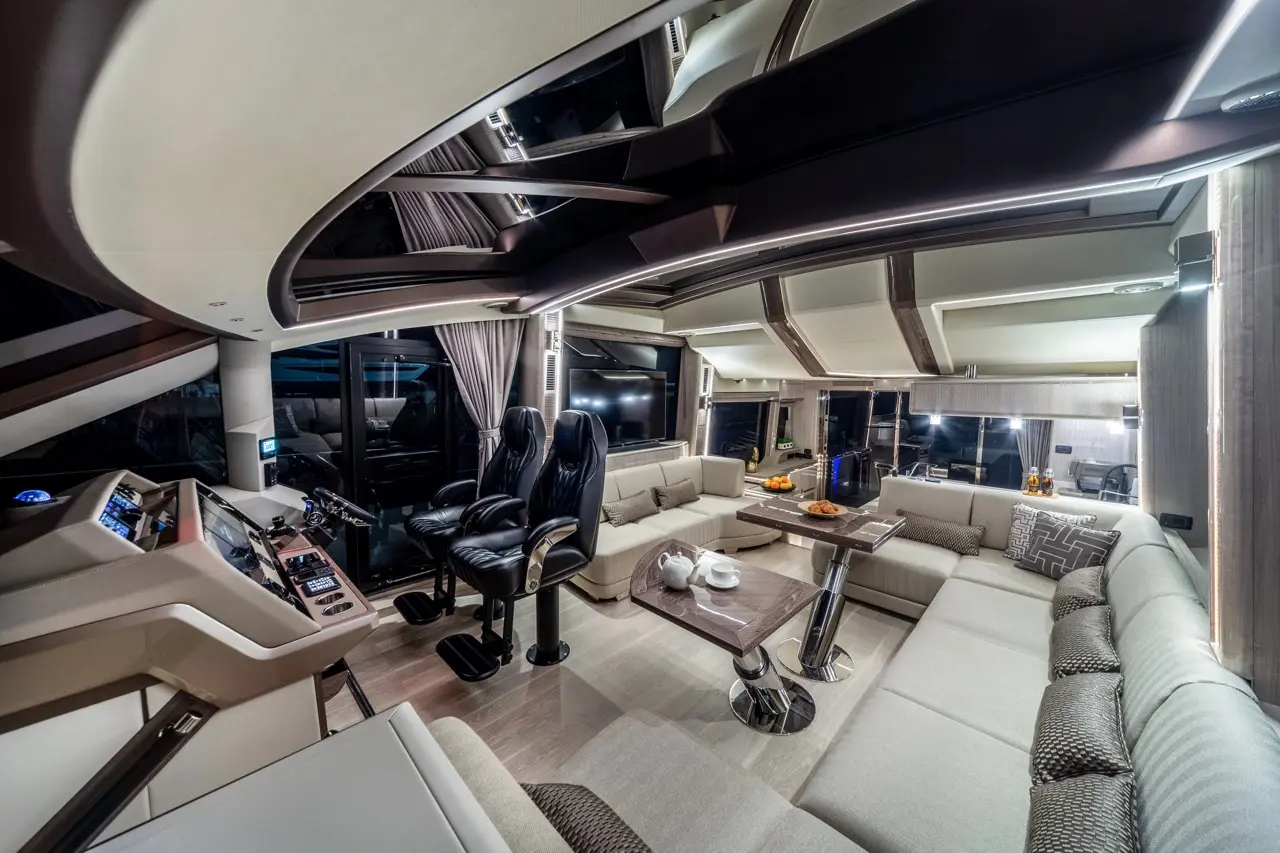 Luxurious yacht interior features a control panel, plush seating, and a dining area with snacks, showcasing modern design.