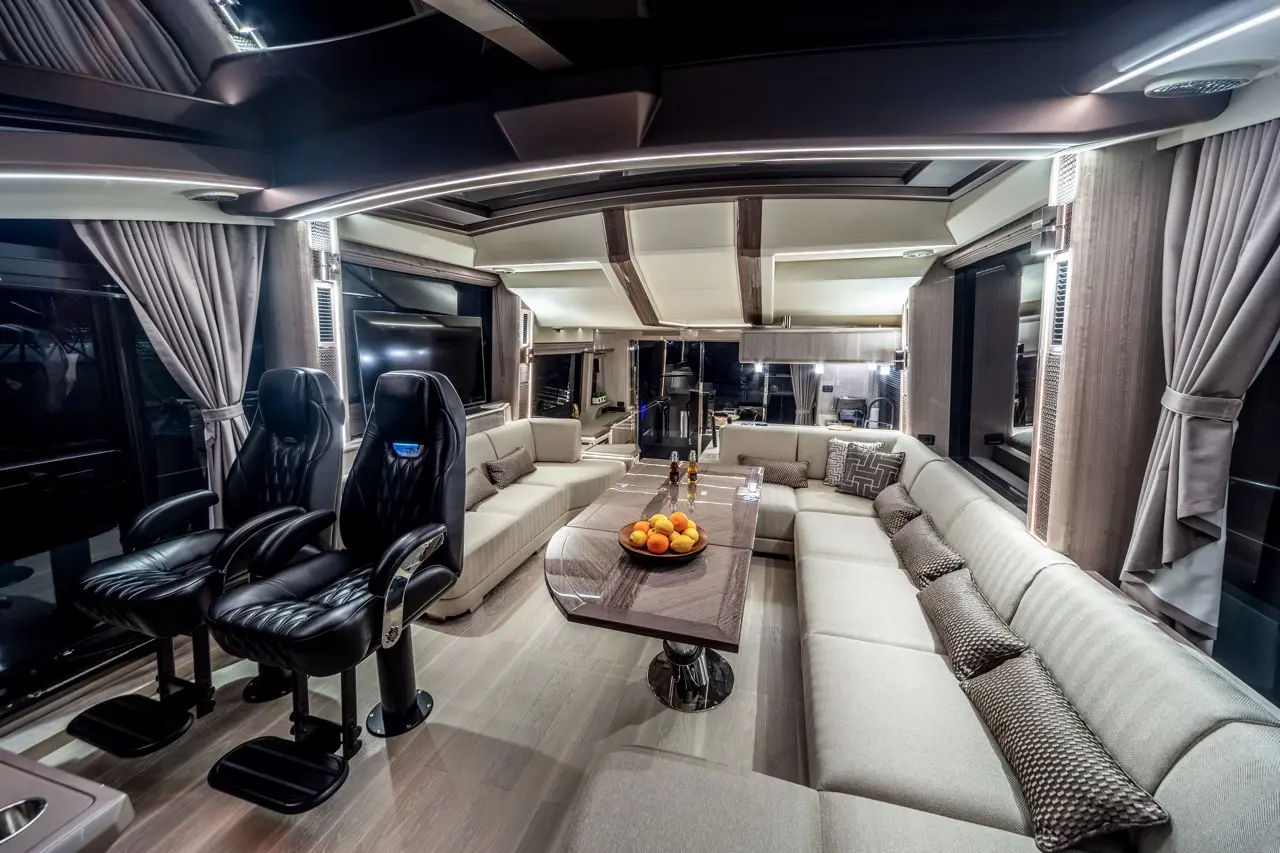 Luxurious lounge featuring black leather swivel chairs, a marble table with fruit, and a spacious sofa in stylish décor.