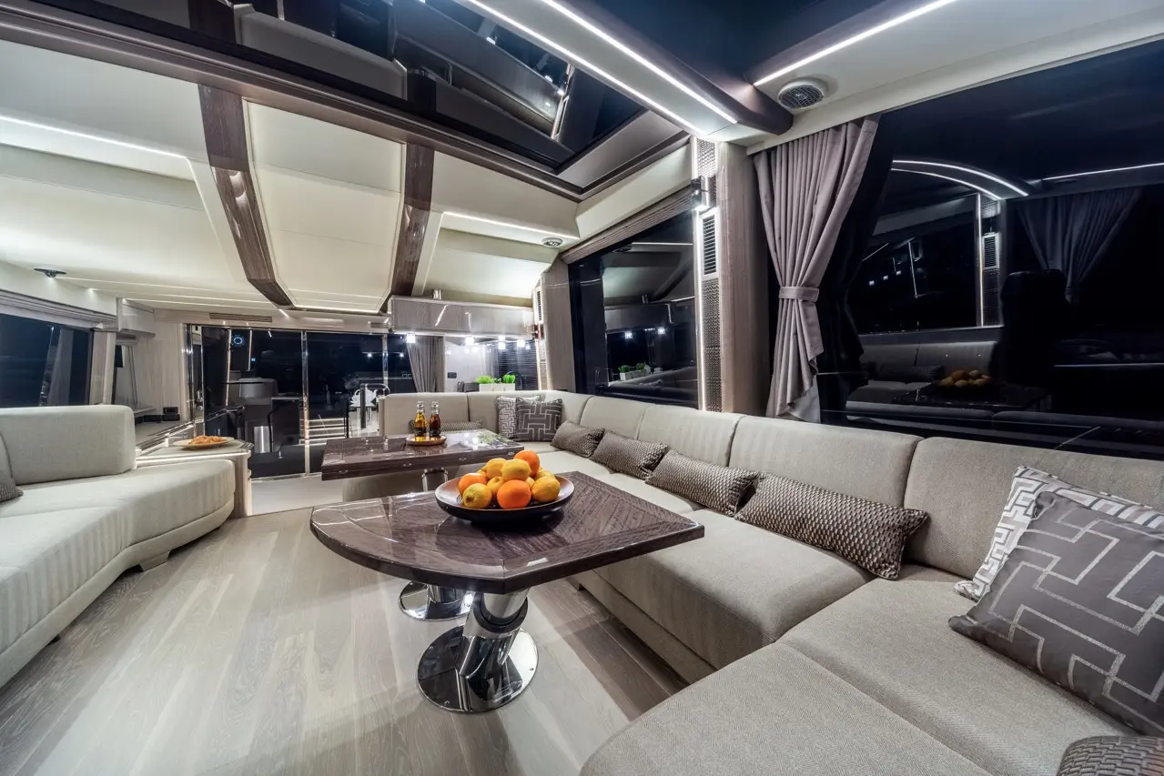 Luxurious yacht interior featuring a grey sofa, circular table with a fruit bowl, and ambient lighting, creating a modern aesthetic.