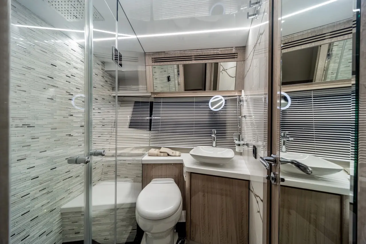 Modern bathroom featuring a shower, toilet, vanity with a basin, and stylish tiled wall, illuminated by sleek lighting.