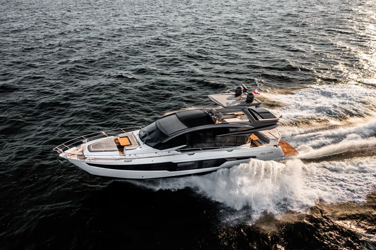 A sleek yacht navigates through waves, leaving a frothy trail on the water, showcasing a luxurious design and modern features.